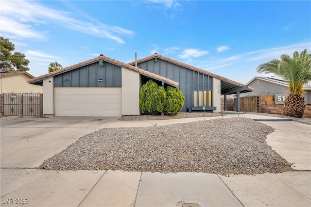 mid-century home featuring an attached garage, a tile roof, driveway, and fence