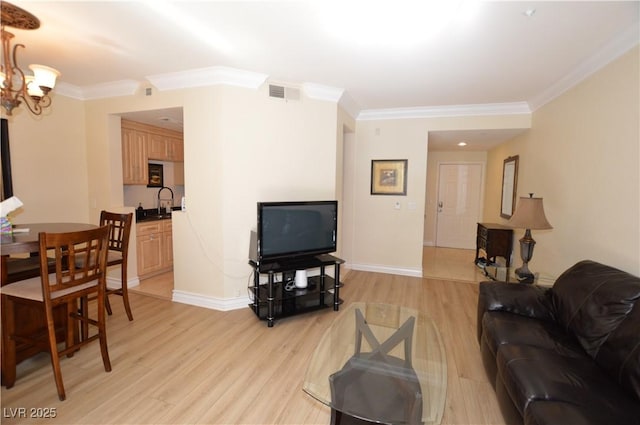 living room featuring visible vents, light wood-style flooring, ornamental molding, baseboards, and a chandelier