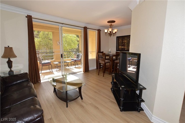 living area with baseboards, an inviting chandelier, crown molding, and light wood finished floors