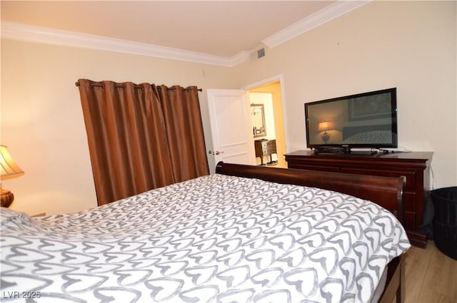 bedroom featuring crown molding, wood finished floors, and visible vents