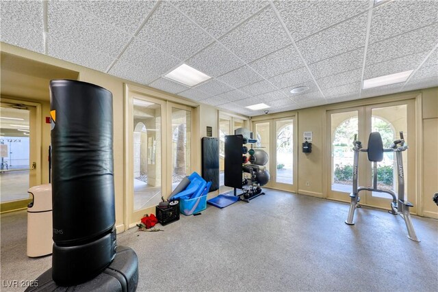 workout area with a drop ceiling, french doors, and baseboards