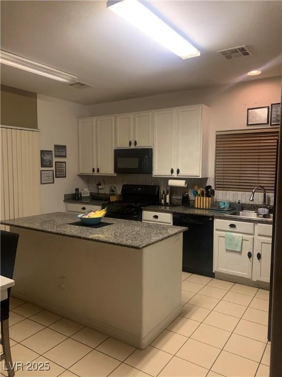 kitchen with visible vents, white cabinetry, black appliances, and a sink