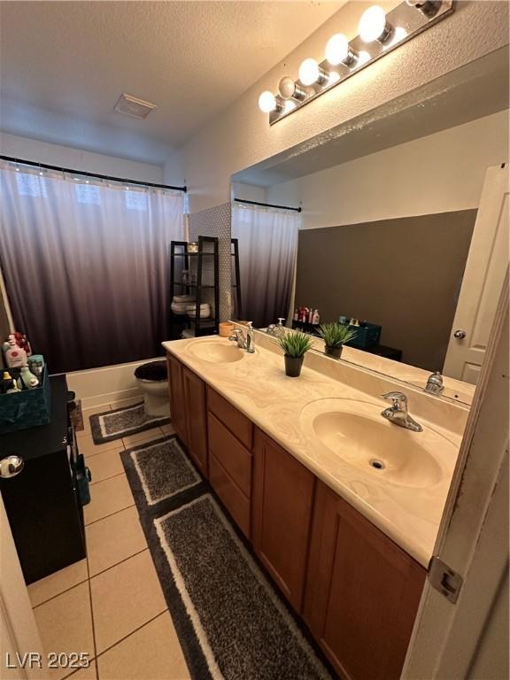 full bath with tile patterned floors, toilet, a textured ceiling, and a sink