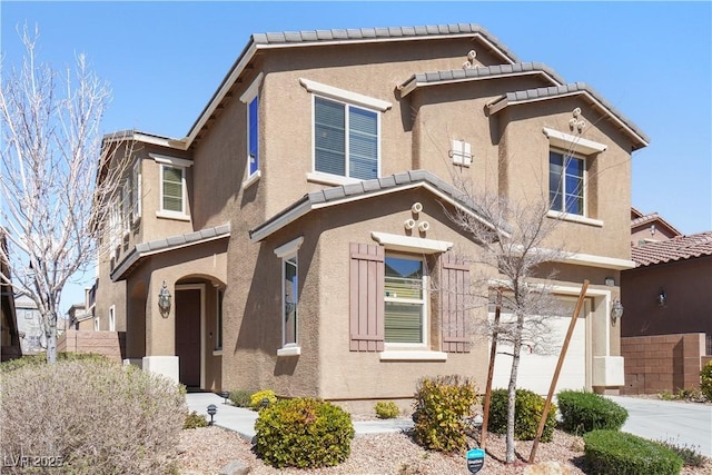 view of front of home with stucco siding, a tiled roof, concrete driveway, and a garage