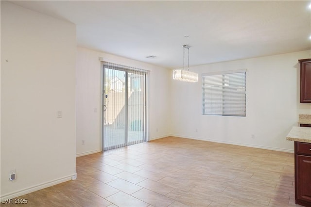 unfurnished dining area featuring a notable chandelier, visible vents, and baseboards