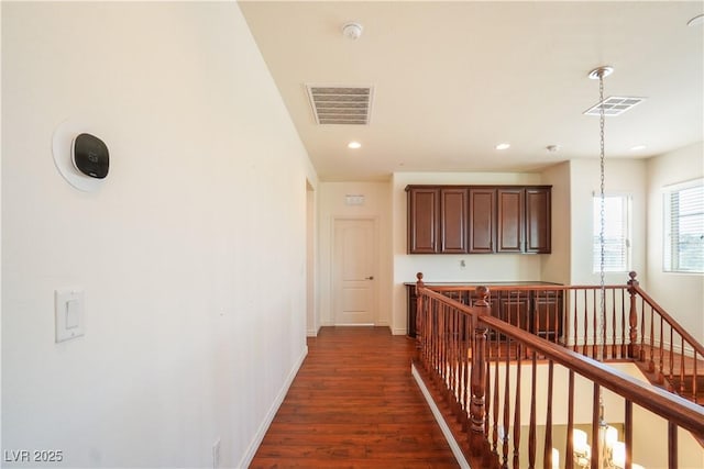 hall with an upstairs landing, visible vents, baseboards, and dark wood-style floors