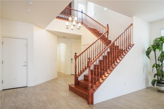 stairs with baseboards, a high ceiling, and an inviting chandelier