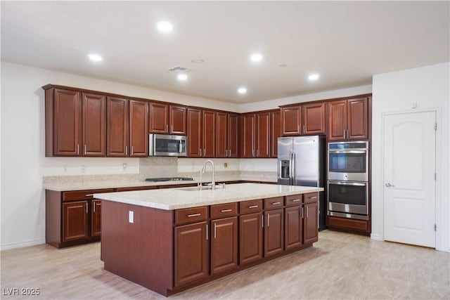 kitchen with visible vents, a kitchen island with sink, a sink, recessed lighting, and stainless steel appliances