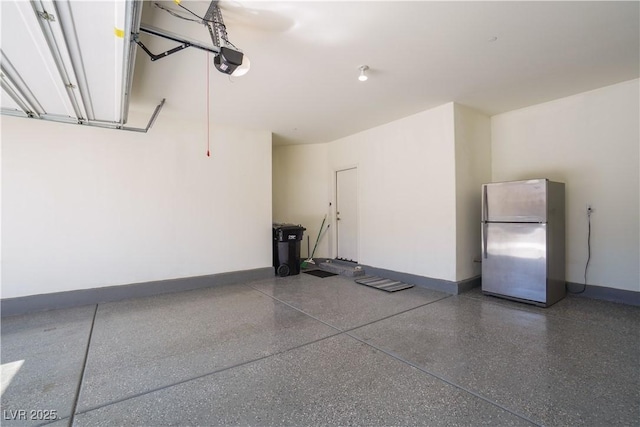 garage featuring baseboards, a garage door opener, and freestanding refrigerator