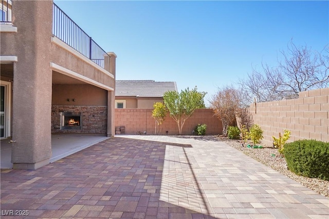 view of patio / terrace with an outdoor stone fireplace and a fenced backyard