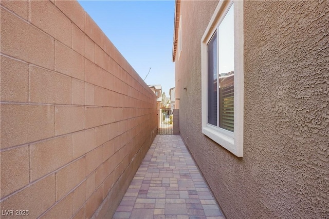 view of side of home with stucco siding and fence