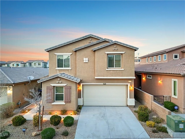 view of front of house with fence, a tiled roof, concrete driveway, stucco siding, and a garage