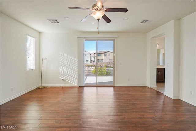 empty room featuring ceiling fan, visible vents, baseboards, and wood finished floors