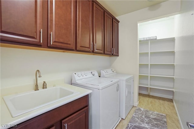 clothes washing area featuring a sink, light wood-type flooring, cabinet space, and washing machine and dryer