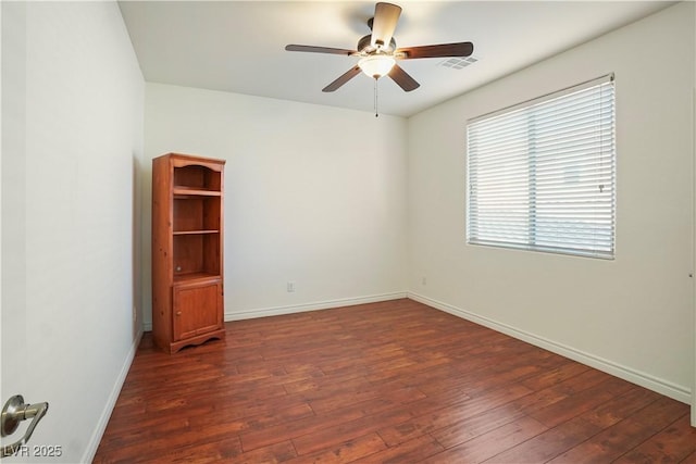 unfurnished room featuring a ceiling fan, dark wood-type flooring, visible vents, and baseboards