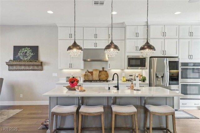 kitchen with stainless steel appliances, visible vents, light wood-style flooring, and white cabinetry