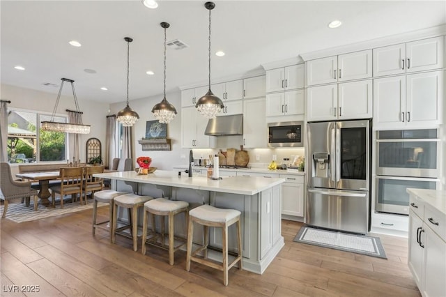 kitchen with light wood finished floors, stainless steel appliances, and light countertops