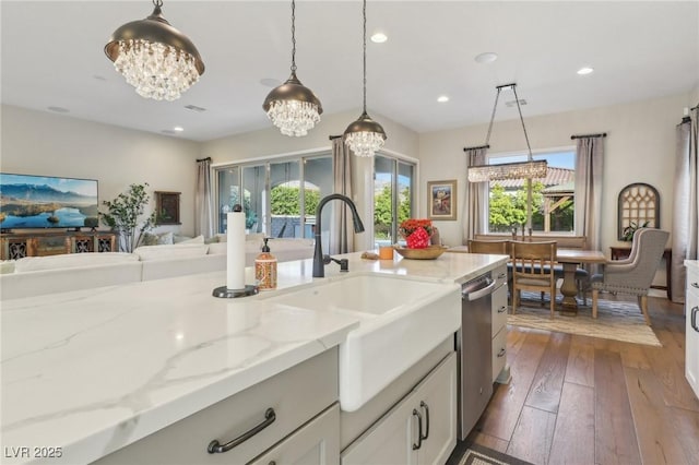 kitchen featuring light stone counters, a chandelier, dark wood finished floors, and hanging light fixtures