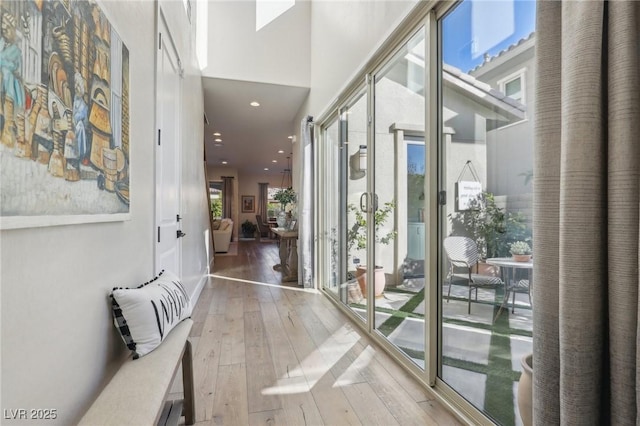 doorway to outside with recessed lighting, a high ceiling, and hardwood / wood-style flooring