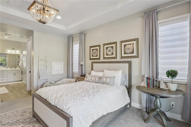 bedroom featuring recessed lighting, ensuite bathroom, a raised ceiling, carpet flooring, and a chandelier