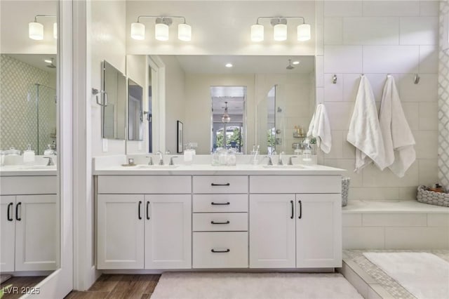 full bathroom with a sink, tiled shower, and double vanity