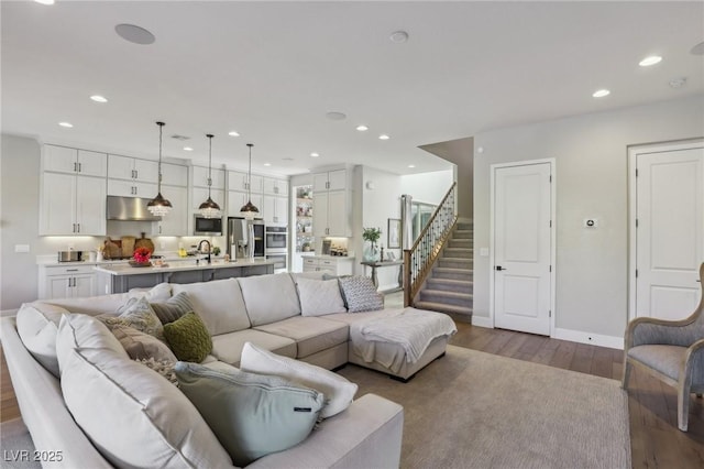 living area with recessed lighting, stairs, baseboards, and wood finished floors