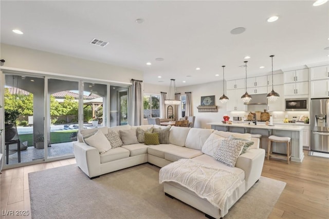 living area with light wood-type flooring, visible vents, and recessed lighting