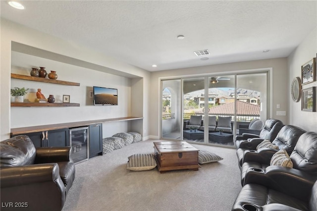 carpeted living area with recessed lighting, visible vents, a textured ceiling, and beverage cooler