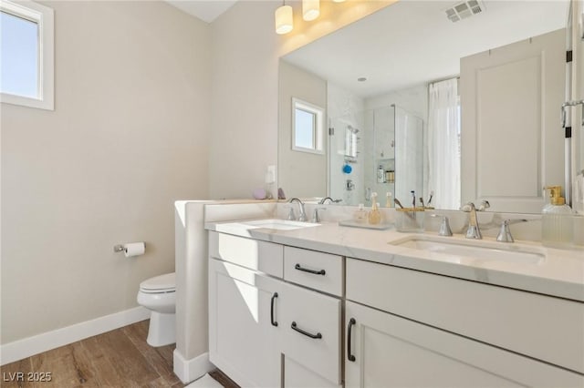 bathroom featuring visible vents, a stall shower, toilet, and a sink