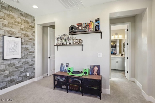 hall with visible vents, baseboards, an accent wall, and carpet