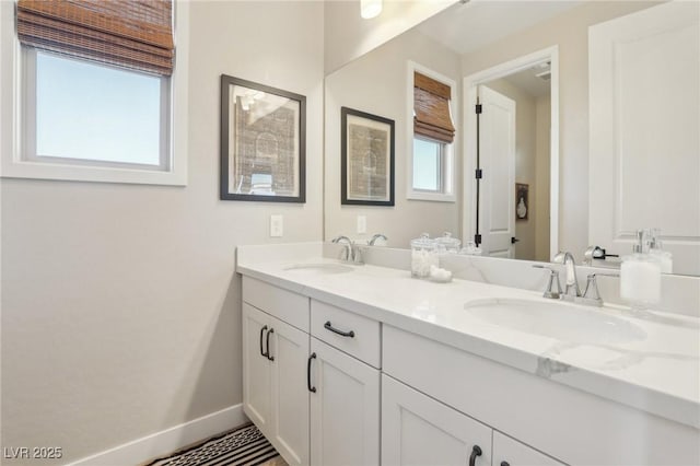 bathroom with double vanity, baseboards, and a sink