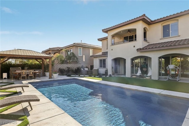 back of house featuring a balcony, a ceiling fan, fence, a gazebo, and a patio area