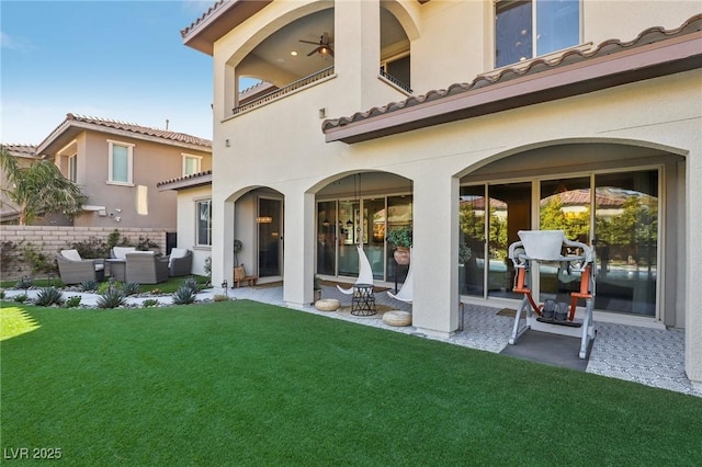 rear view of house with an outdoor living space, a lawn, a balcony, and stucco siding