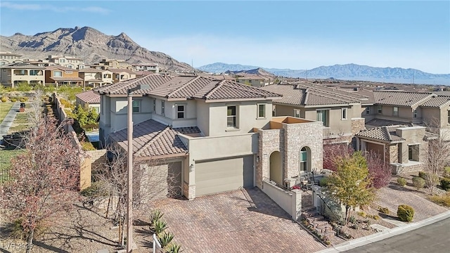 view of front of home with a mountain view, decorative driveway, a residential view, and stucco siding