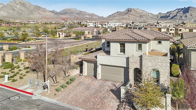 mediterranean / spanish home featuring decorative driveway, a residential view, a mountain view, and stucco siding