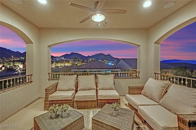 patio terrace at dusk featuring outdoor lounge area, a balcony, a mountain view, and ceiling fan