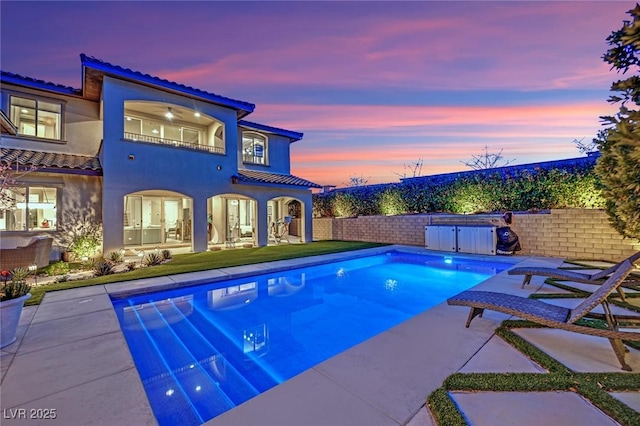 pool at dusk featuring a patio area, a fenced in pool, and a fenced backyard