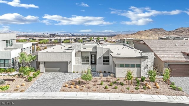 view of front of property featuring decorative driveway, an attached garage, a mountain view, stucco siding, and a residential view