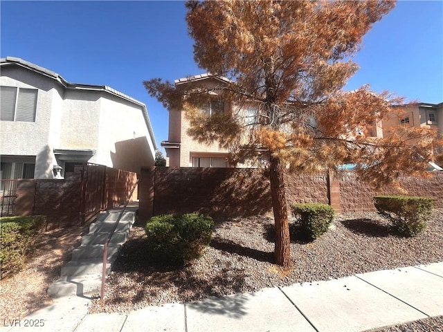 view of side of property featuring a fenced front yard, stucco siding, and a gate