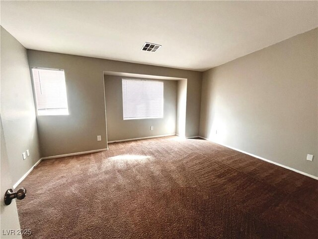 carpeted empty room featuring baseboards and visible vents