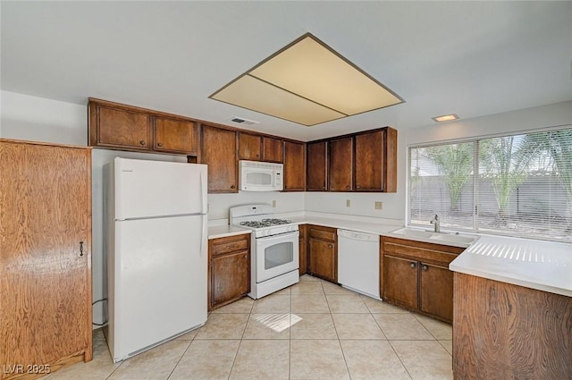 kitchen with white appliances, visible vents, light tile patterned flooring, a sink, and light countertops