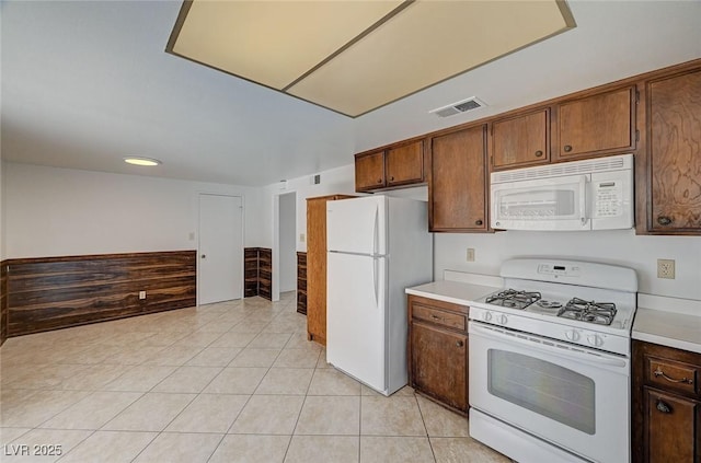 kitchen with white appliances, light tile patterned floors, light countertops, and visible vents