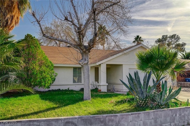 view of front of property featuring a shingled roof, a front yard, and stucco siding