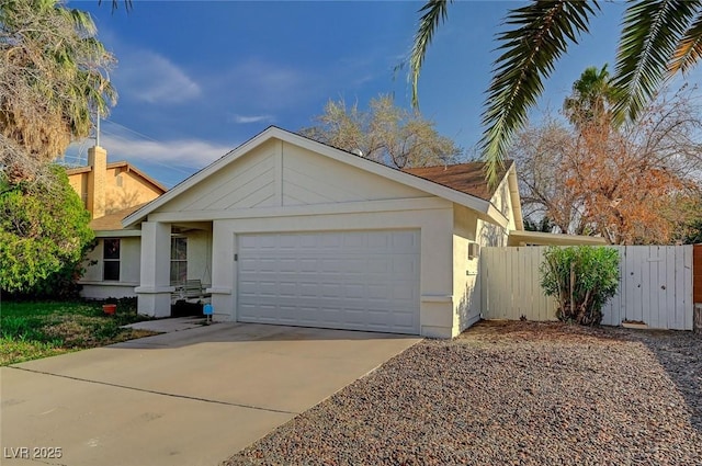 view of front of home with stucco siding, driveway, an attached garage, and fence