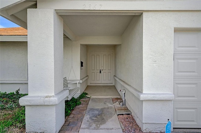 entrance to property with stucco siding and an attached garage