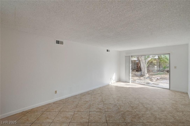 tiled spare room with visible vents, a textured ceiling, and baseboards