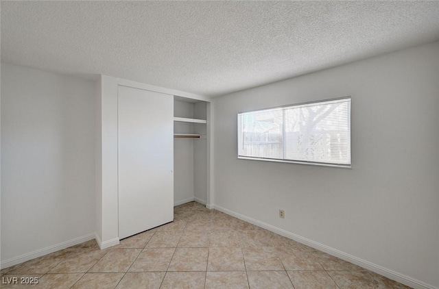 unfurnished bedroom featuring light tile patterned flooring, baseboards, a textured ceiling, and a closet