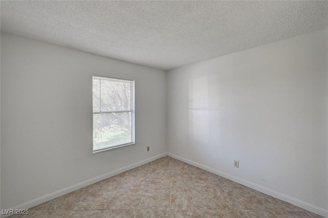 spare room with a textured ceiling and baseboards