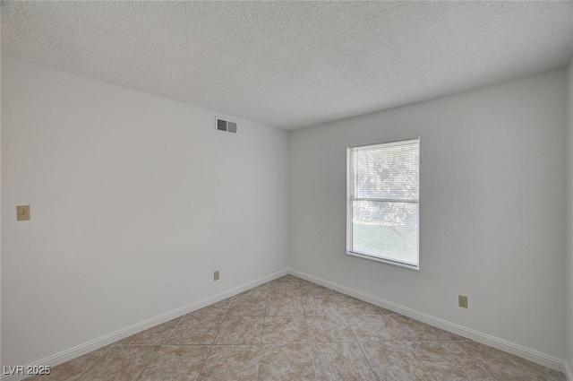 spare room with visible vents, baseboards, and a textured ceiling