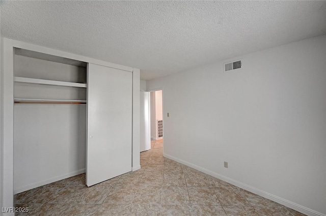 unfurnished bedroom featuring visible vents, baseboards, a textured ceiling, and a closet